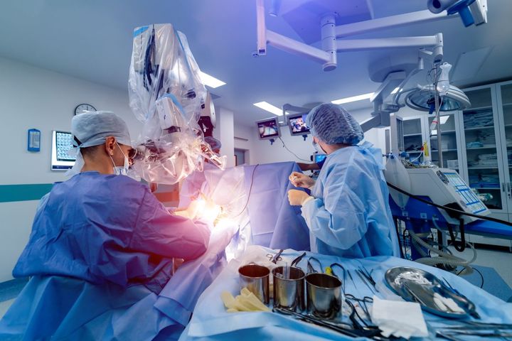 Physicians and nurses oversee an artificial intelligence-enable robotic surgical procedure.