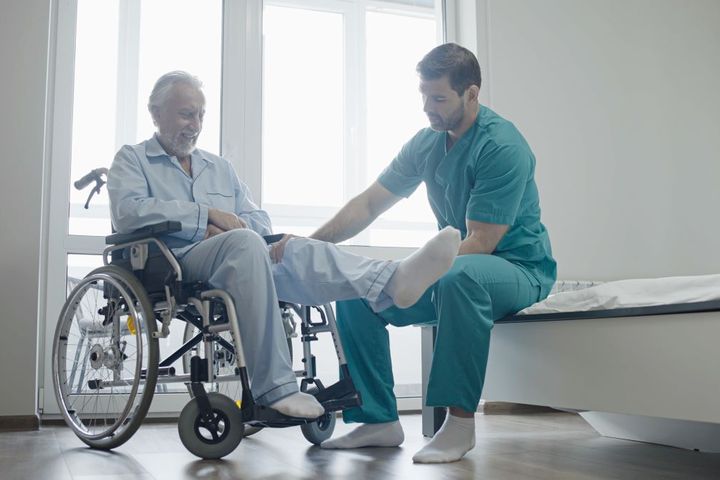 A nurse assists a patient who has his leg in a cast.