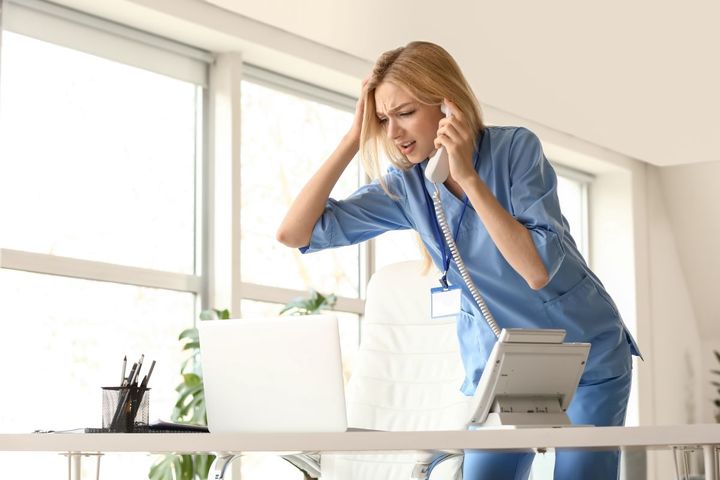 A nurse on the telephone, looking angry, in need of some conflict resolution.