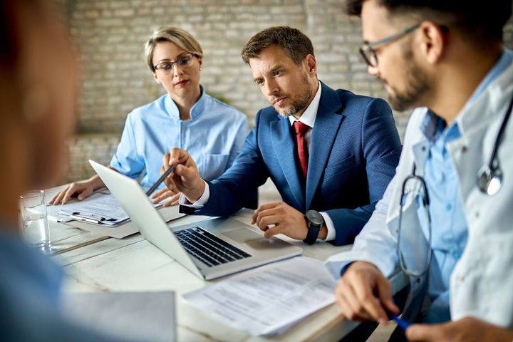 A healthcare organization's CFO goes over the revenue reports with other members of the senior staff.