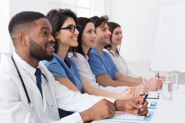 A group of doctors and nursing sit for a healthcare staff training session.