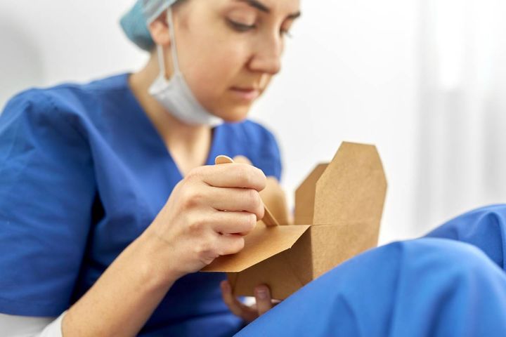 A nurse eats noodles and vegetables, one of the top healthy snacks for night shift.