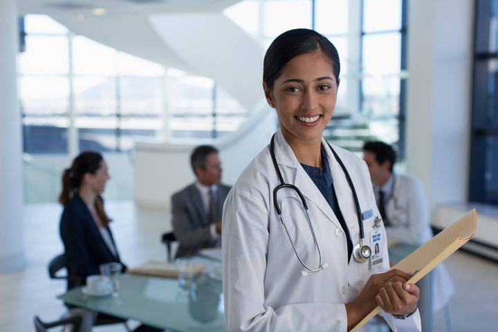 A hospitalist nurse practitioner poses for a photo after meeting with hospital administrators.