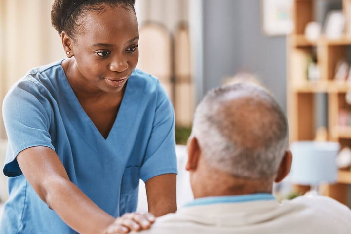 African-American nurse with her hand on the shoulder of a senior patient.