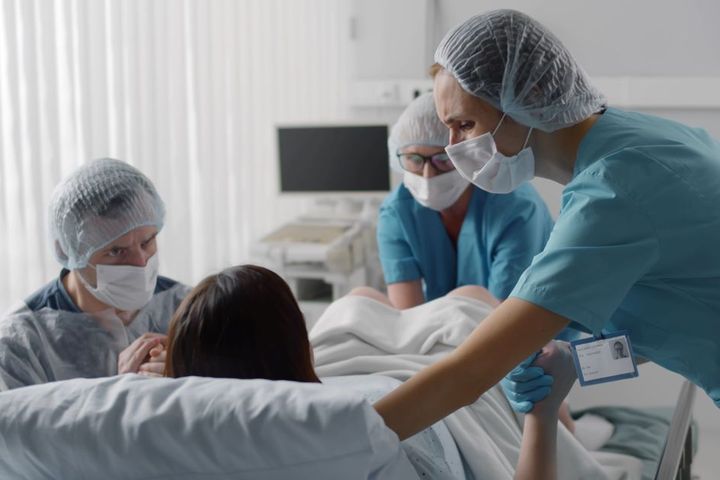 A labor and delivery nurse assists other staff with a delivery.