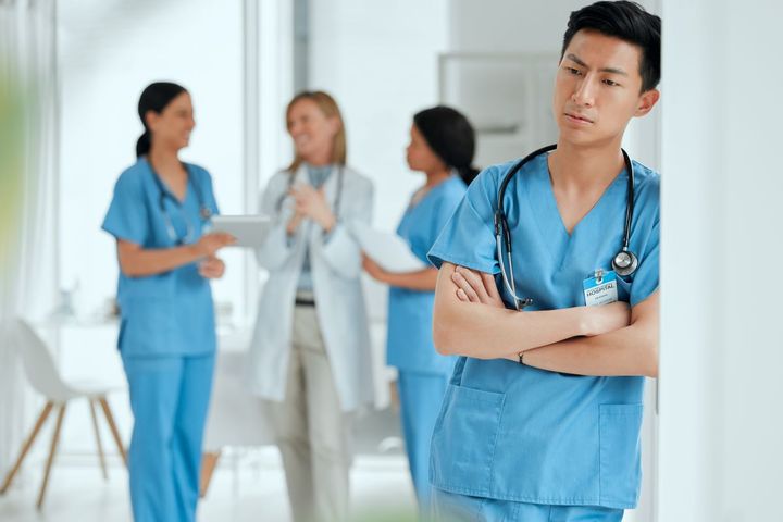 A nurse stands alone, while his colleagues carry on together.