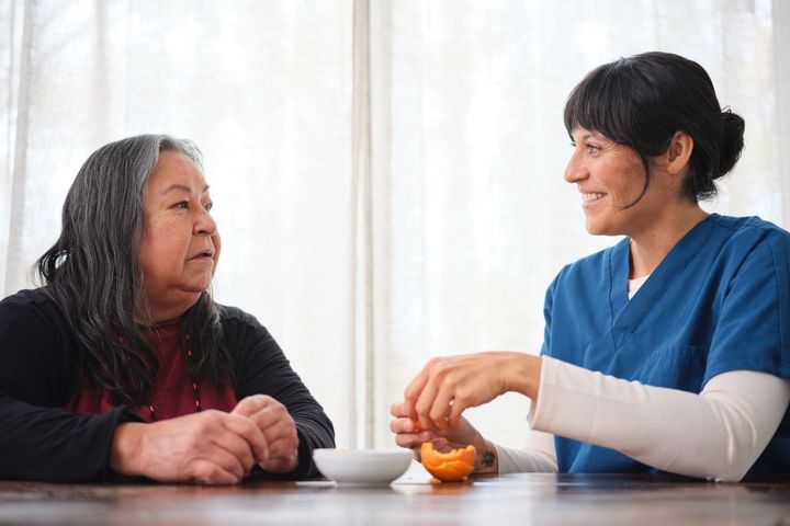 A nurse meets the first of Maslow's hierarchy of needs in nursing while helping a patient with a meal.