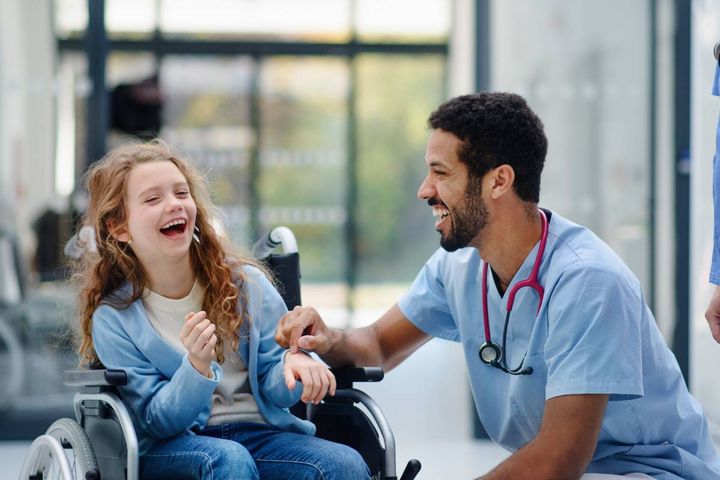 A nurse tells a patient one of his favorite nurse jokes and they laugh.