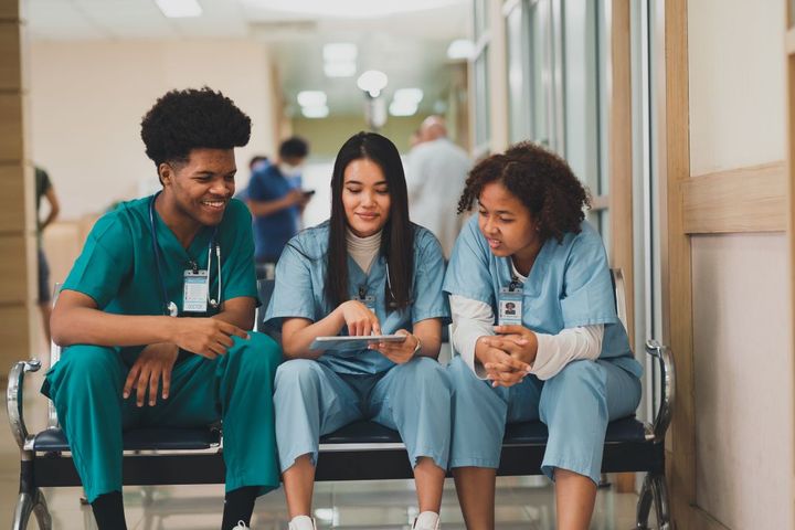 Three nurses sitting on a bench and talking to one another
