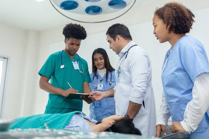 A group of nursing students reviews nursing medical terminology with their professor.
