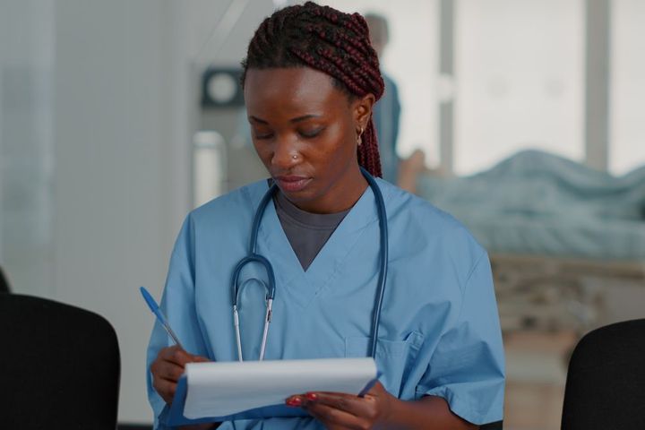 An OB-GYN nurse takes notes as she meets with a patient.