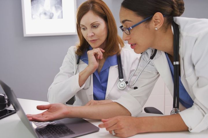 A physician's assistant and her supervising physician discuss a patient's chart.