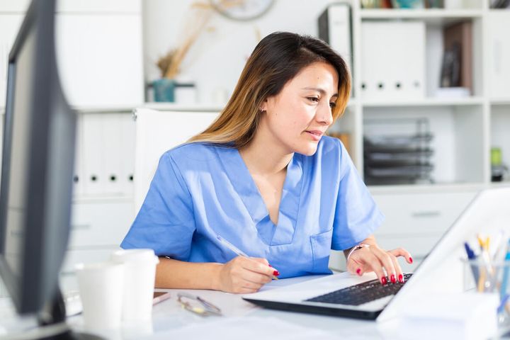 Latina nurse working on her cover letter on a laptop.