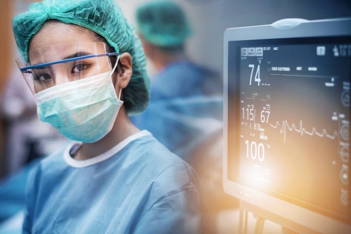 A nurse in the SICU poses for a photo by a monitor.