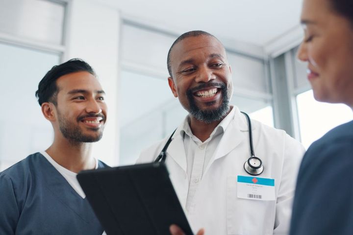 Two nurses have a jovial conversation with a physician.