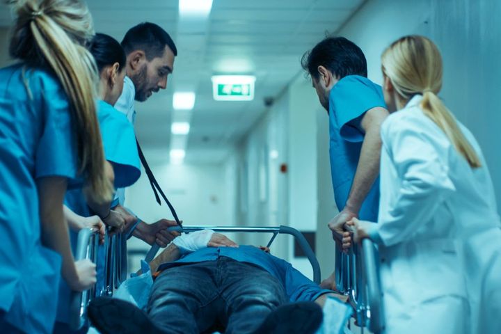 A doctor and attending trauma nurses rush a patient to a hospital room.
