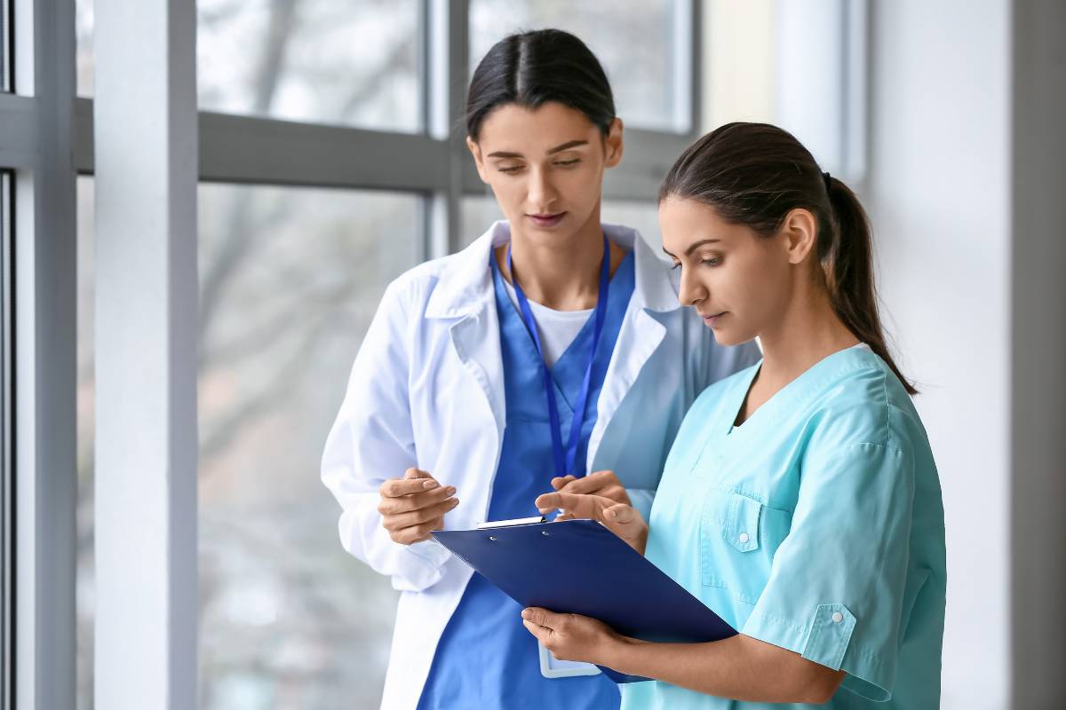 A nurse practitioner with ACNP-BC certification consults with a colleague.