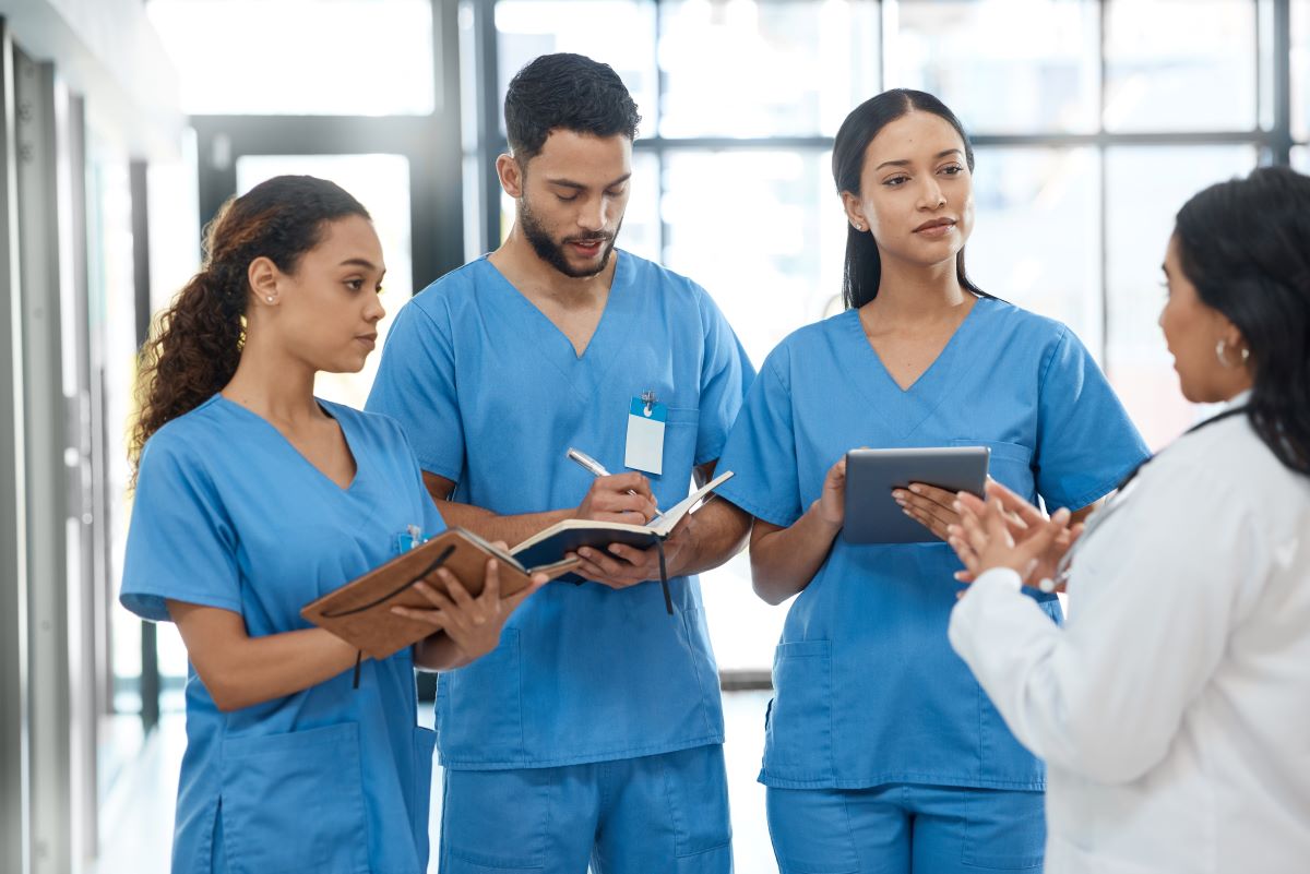 A nursing staff takes notes while listening to a physician's instructions.