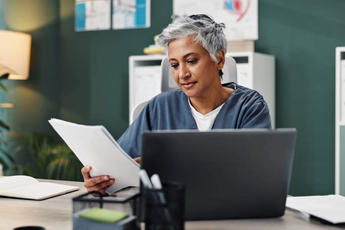 A healthcare professional reviews advance directives, nursing considerations, and patient care instructions before a patient intake.