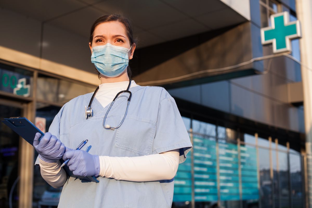 A nurse wearing a medical mask greets patients at a medical clinic.