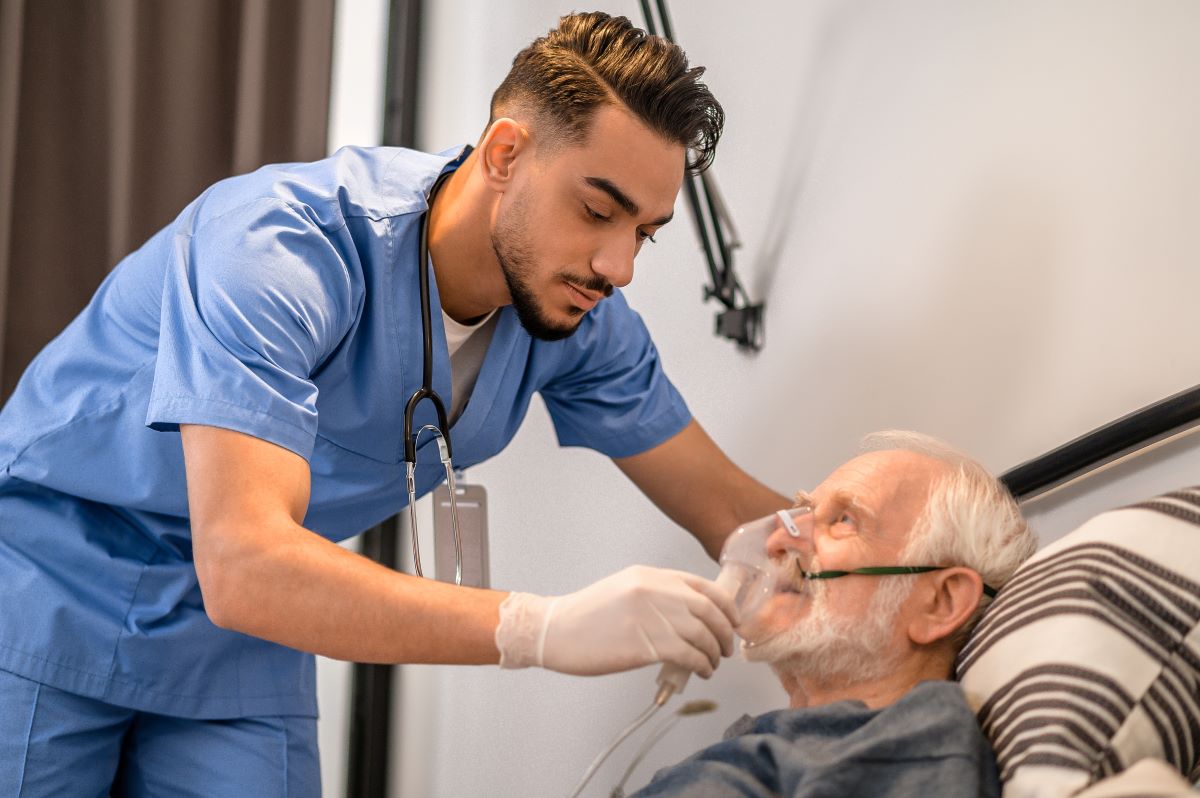 A nurse helps adjust an oxygen mask for an elderly patient.
