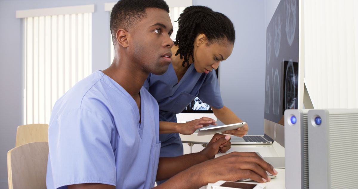 Two nurses look at data and analyze x-ray images.