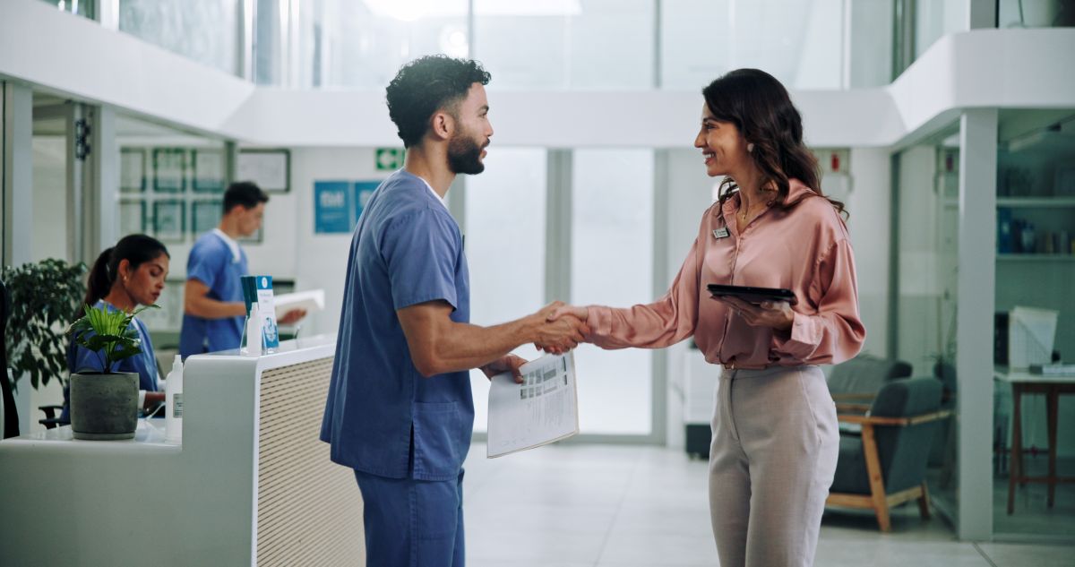 A nurse candidate shakes hands with the supervisor who will interview him.