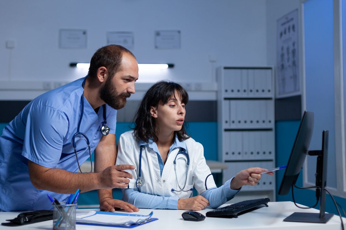 A nurse and a physician check records on a computer.