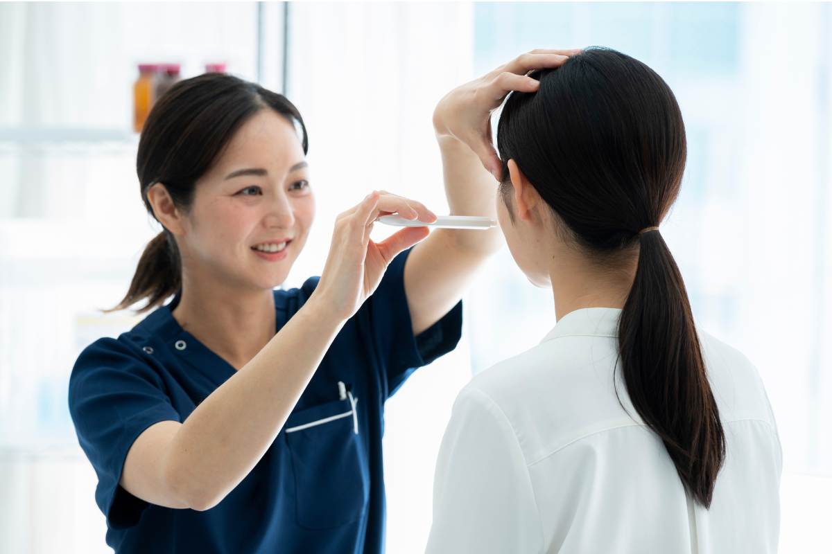 A Certified Aesthetic Nurse Specialist assesses the skin on a patient's face.