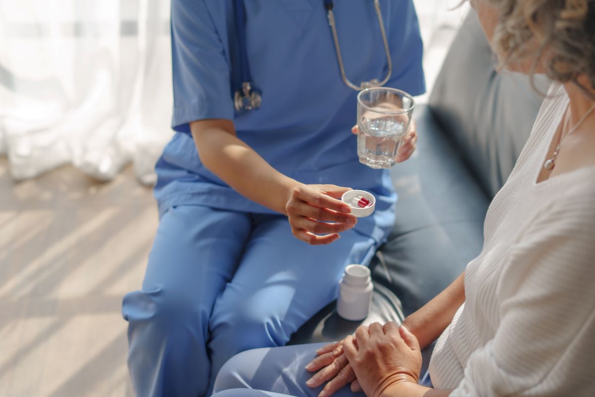 A certified medication aide administers medication to a patient.