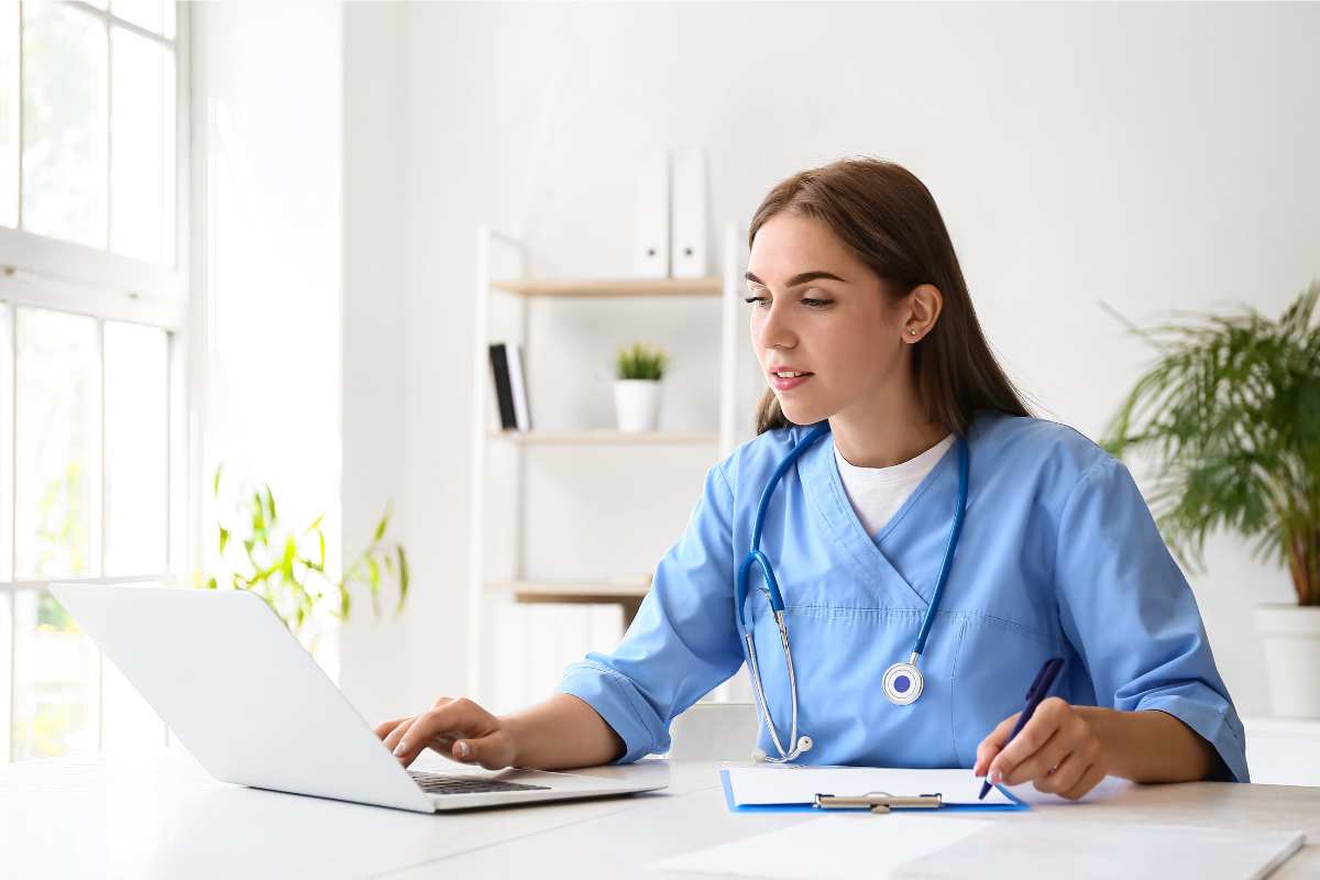 Female clinical research coordinator working on a laptop at a desk.