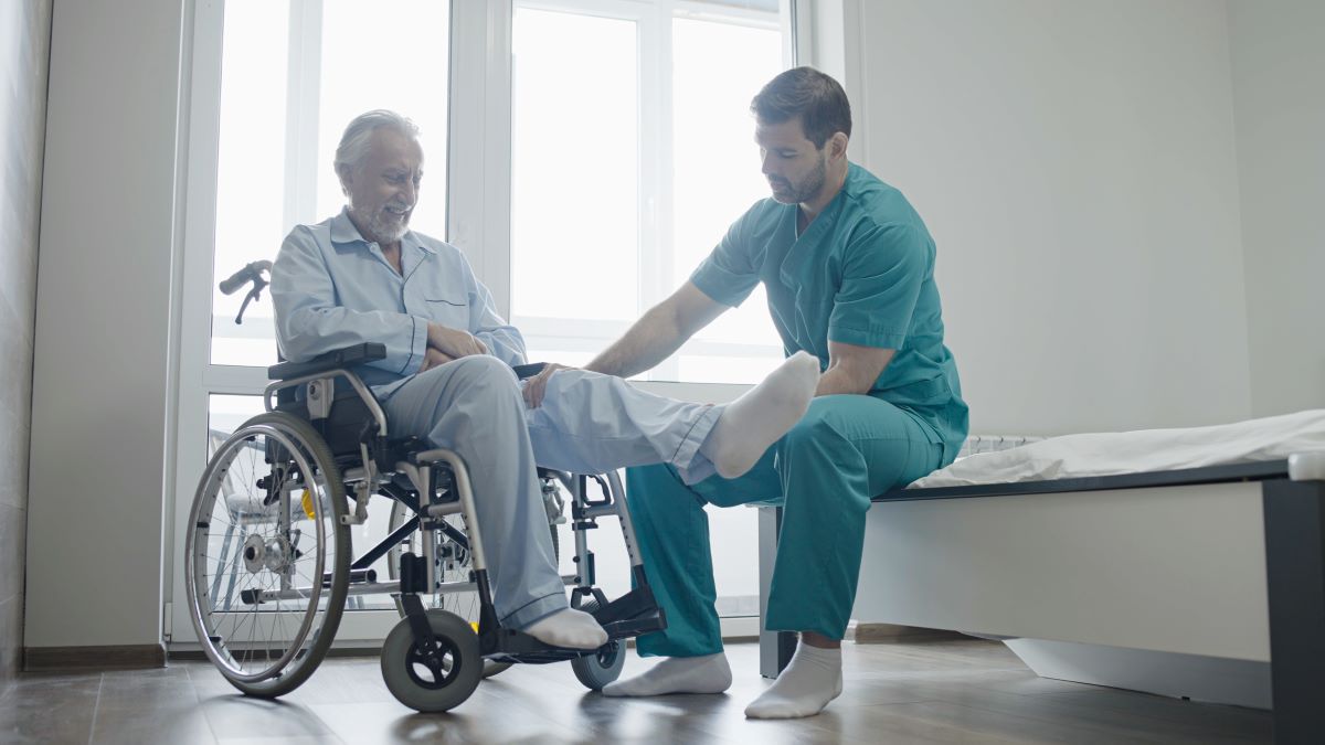 A nurse assists a patient who has his leg in a cast.