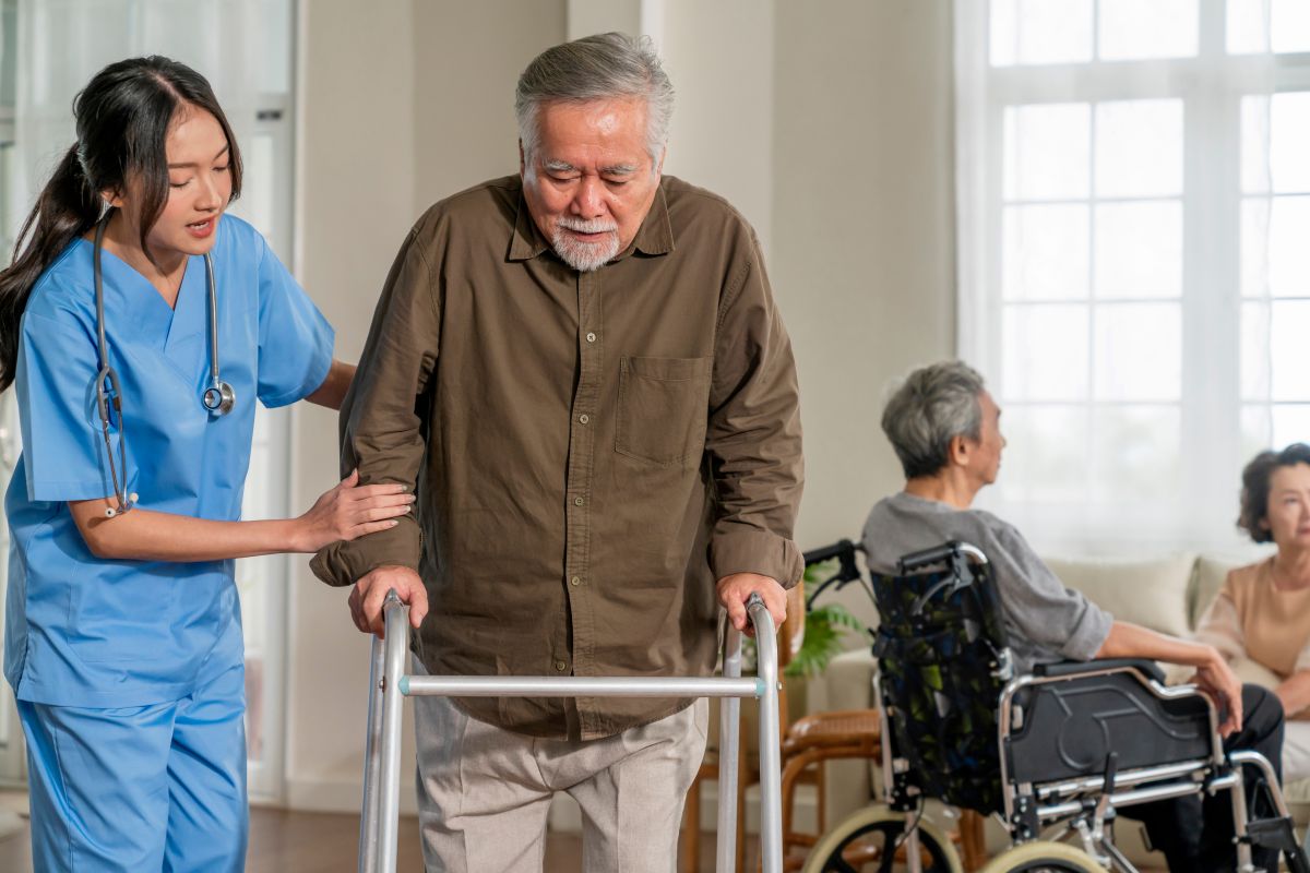 A CNA assists a nursing resident with a walker.