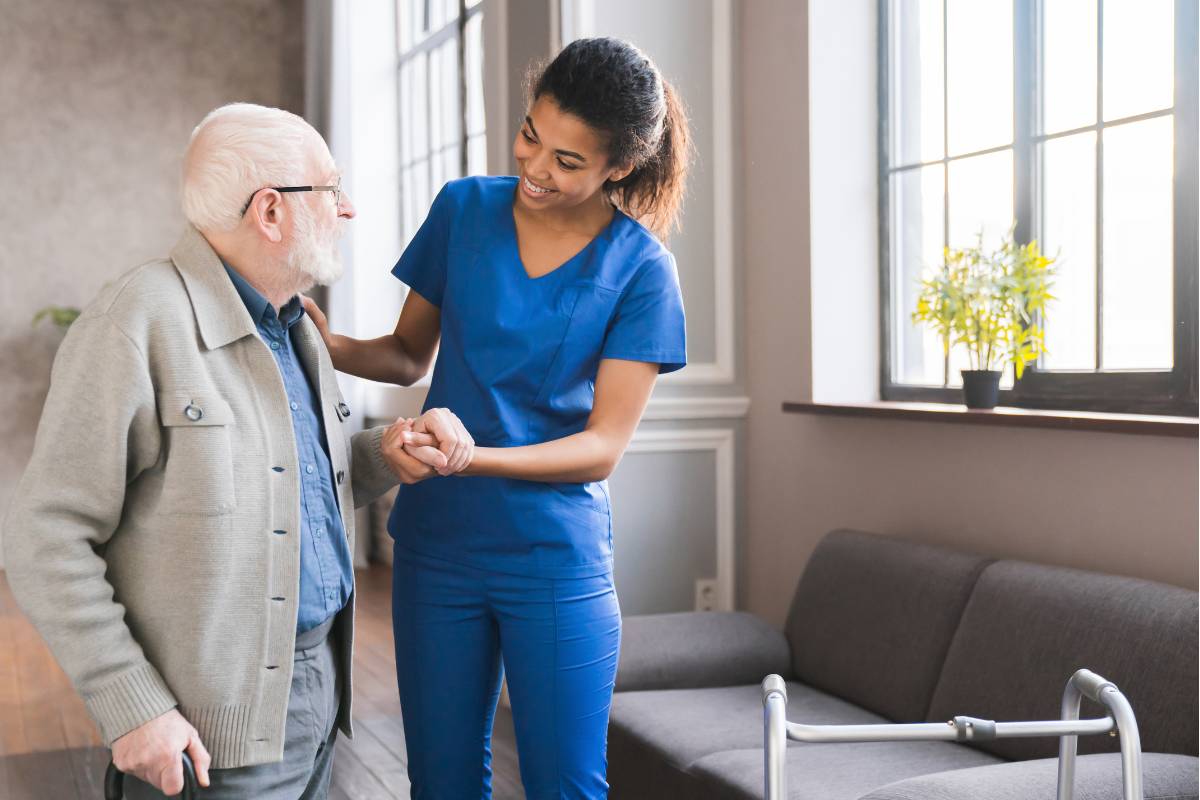 A nurse demonstrates compassionate vs. caring nursing as she helps a patient to his walker.
