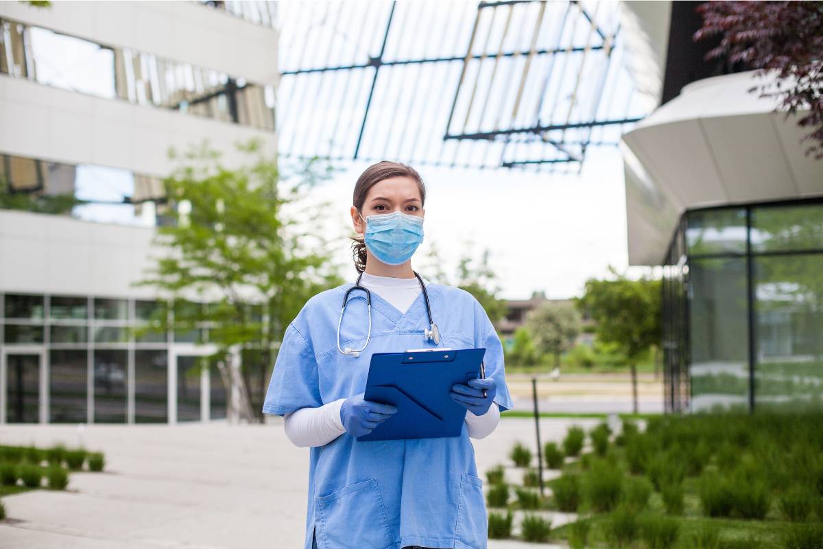 A nurse with CPH certification poses for a photo in hospital atrium.