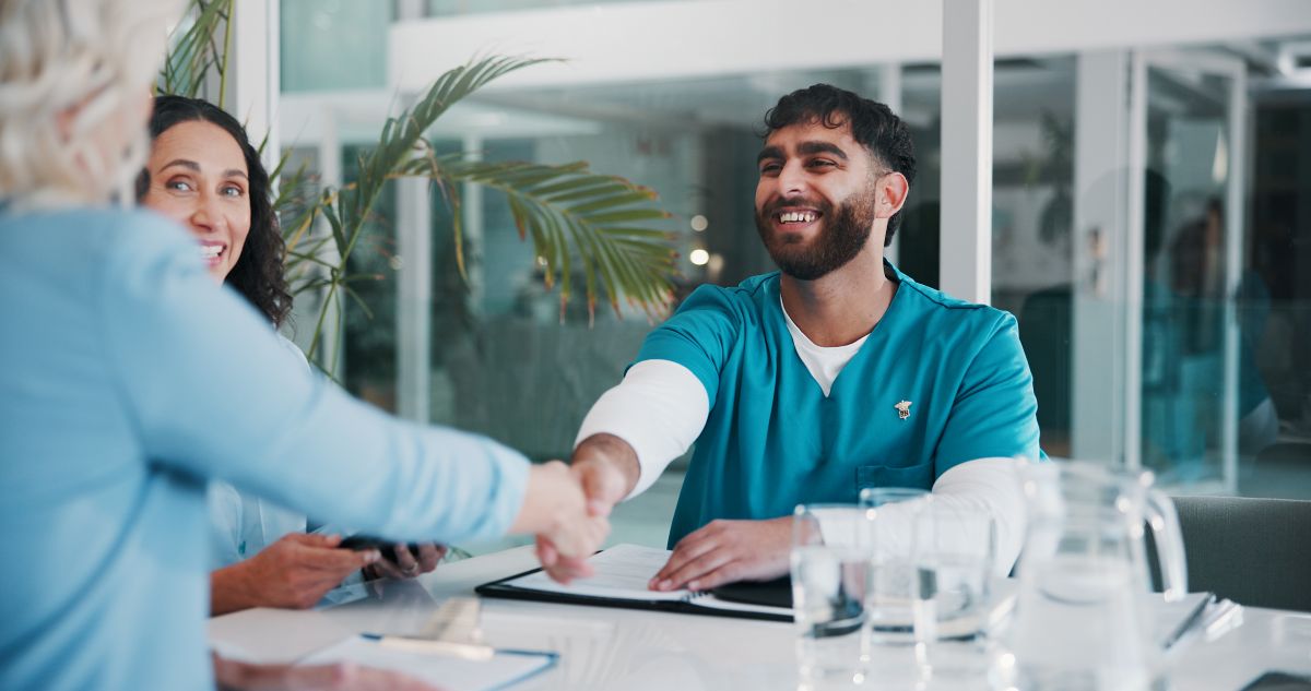 A newly hired nurse shakes the hand of his new supervisor.
