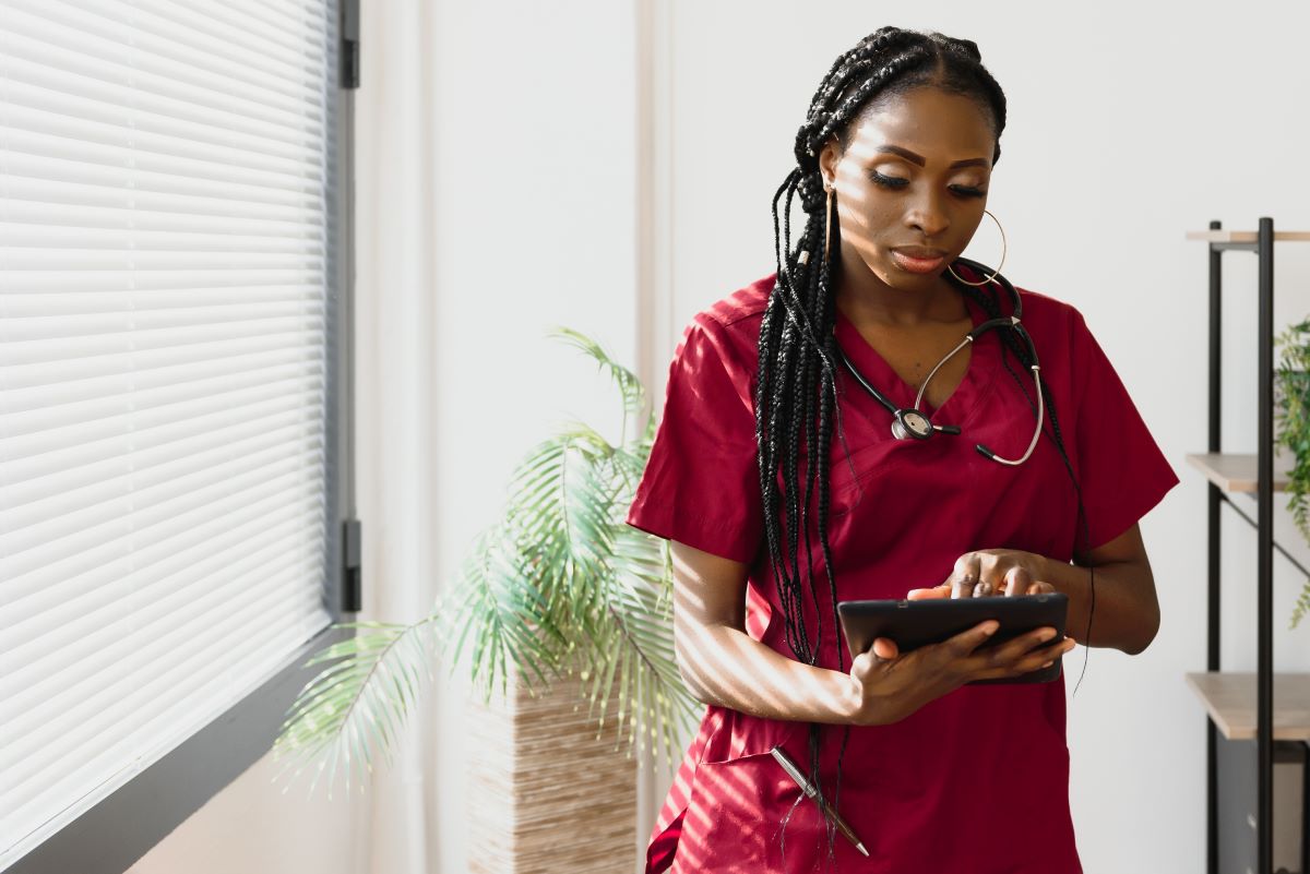 A director of nursing, or DON, standing in her office checking something on a tablet computer.