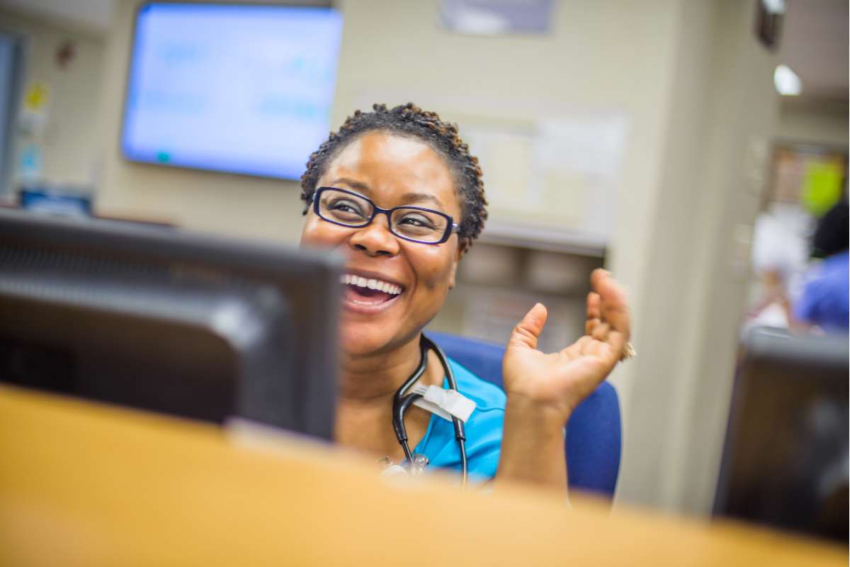 African-American nurse at a desk with a computer taking EHR training.