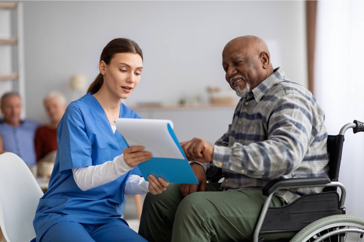An endocrinology nurse practitioner meets with a patient in a wheelchair at a clinic.
