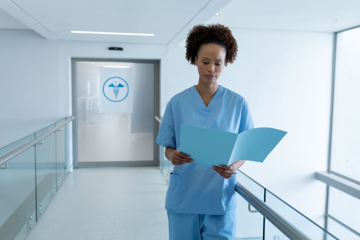A nurse checks a patient chart as she walks down a hospital hallway.