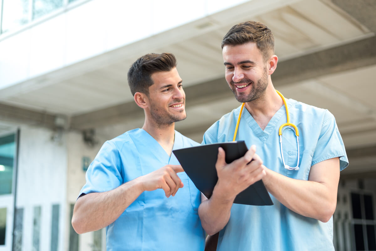 One male nurse explaining to another male nurse what to expect on his first day as a nurse.