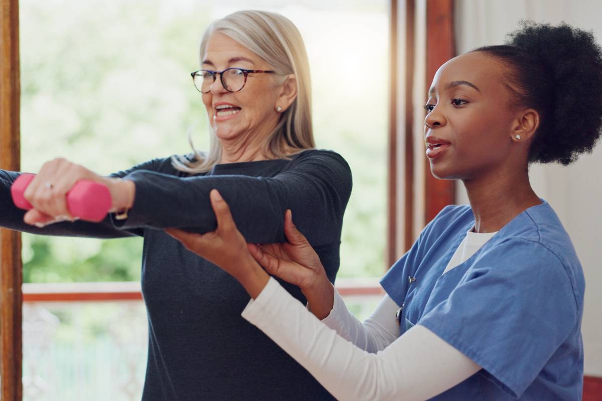A fitness nurse assists a client while they lift weights.
