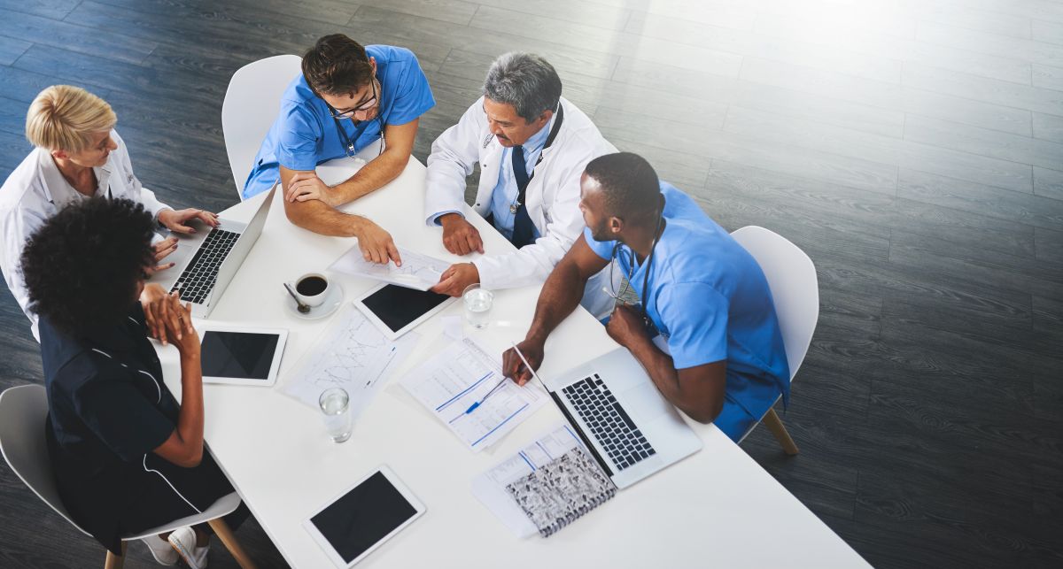 Hospital staff gather at a table and try to fill open positions, with the help of a healthcare ats.