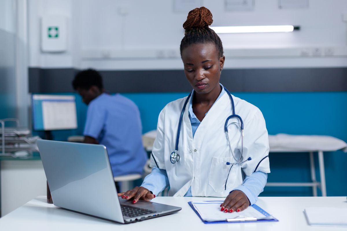 A physician checks patient records on a laptop.
