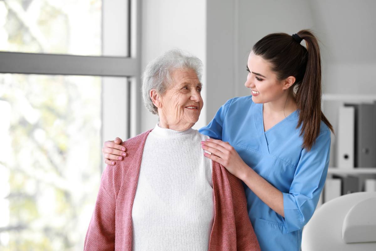 A nurse works with a patient while displaying the traits described in her home health aide cover letter.