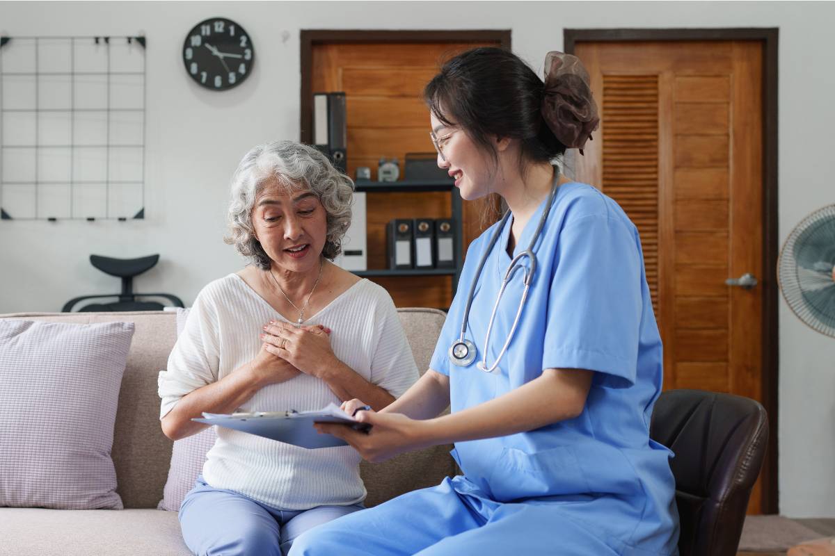 A home health nurse practitioner meets with a patient in their home.