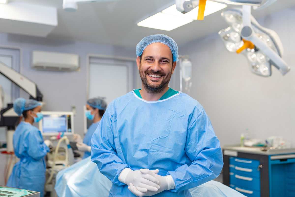 ICU nurse in scrubs and a hair net in a hospital room