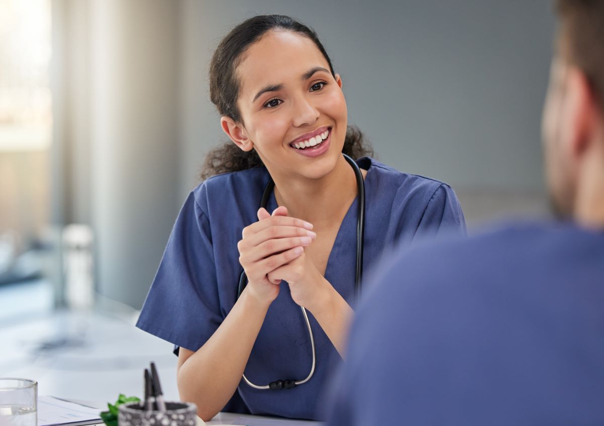 A nurse leader sits down with a colleague to discuss a patient.