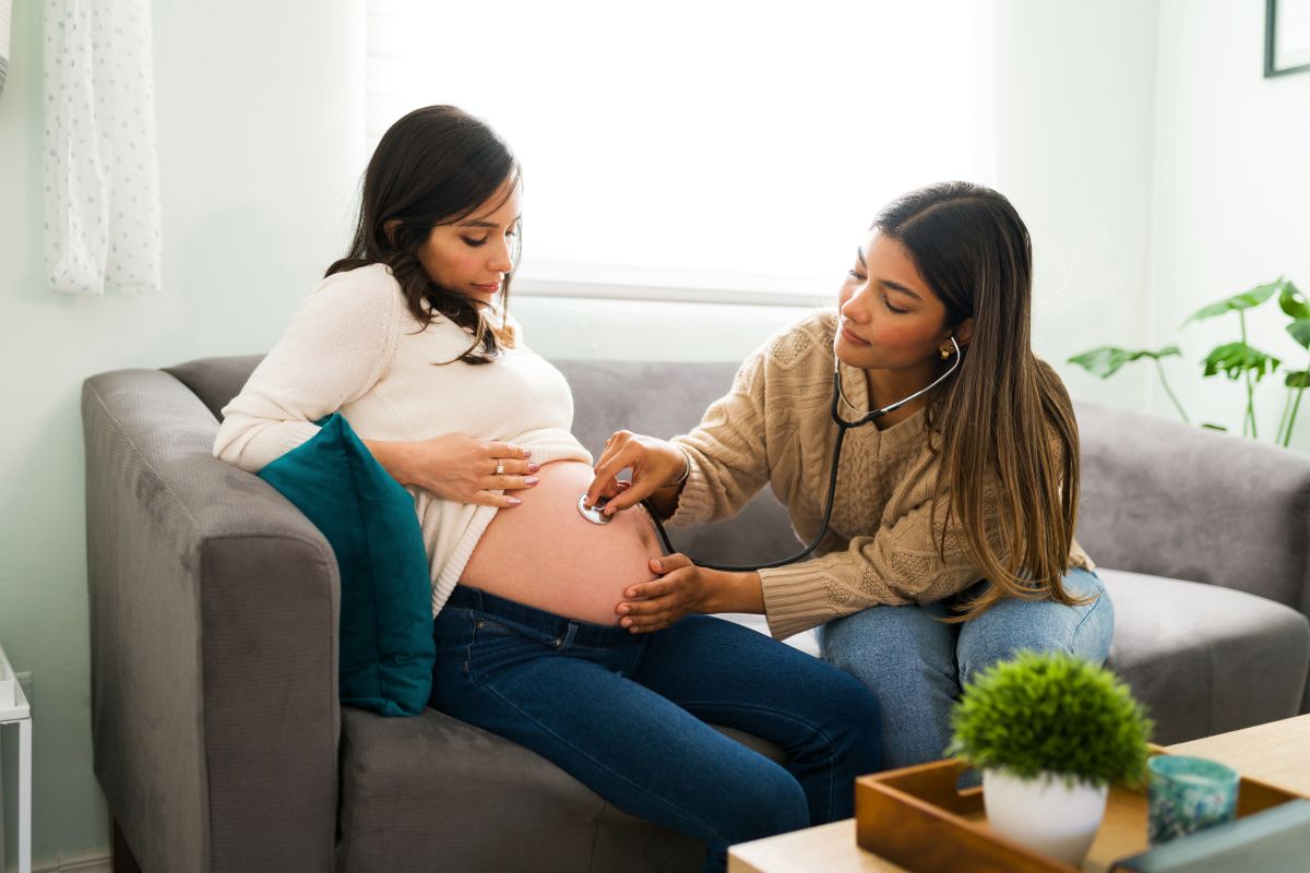 A female midwife assists a pregnant female patient in an office