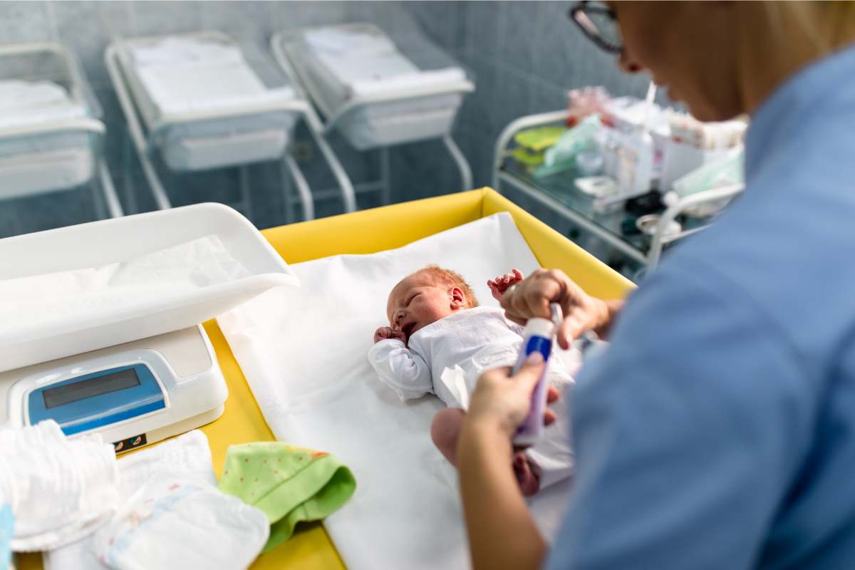 A nurse checking a neonate for pain symptoms